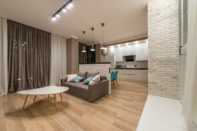 Furnished living room with the couch against a half wall separating the kitchen